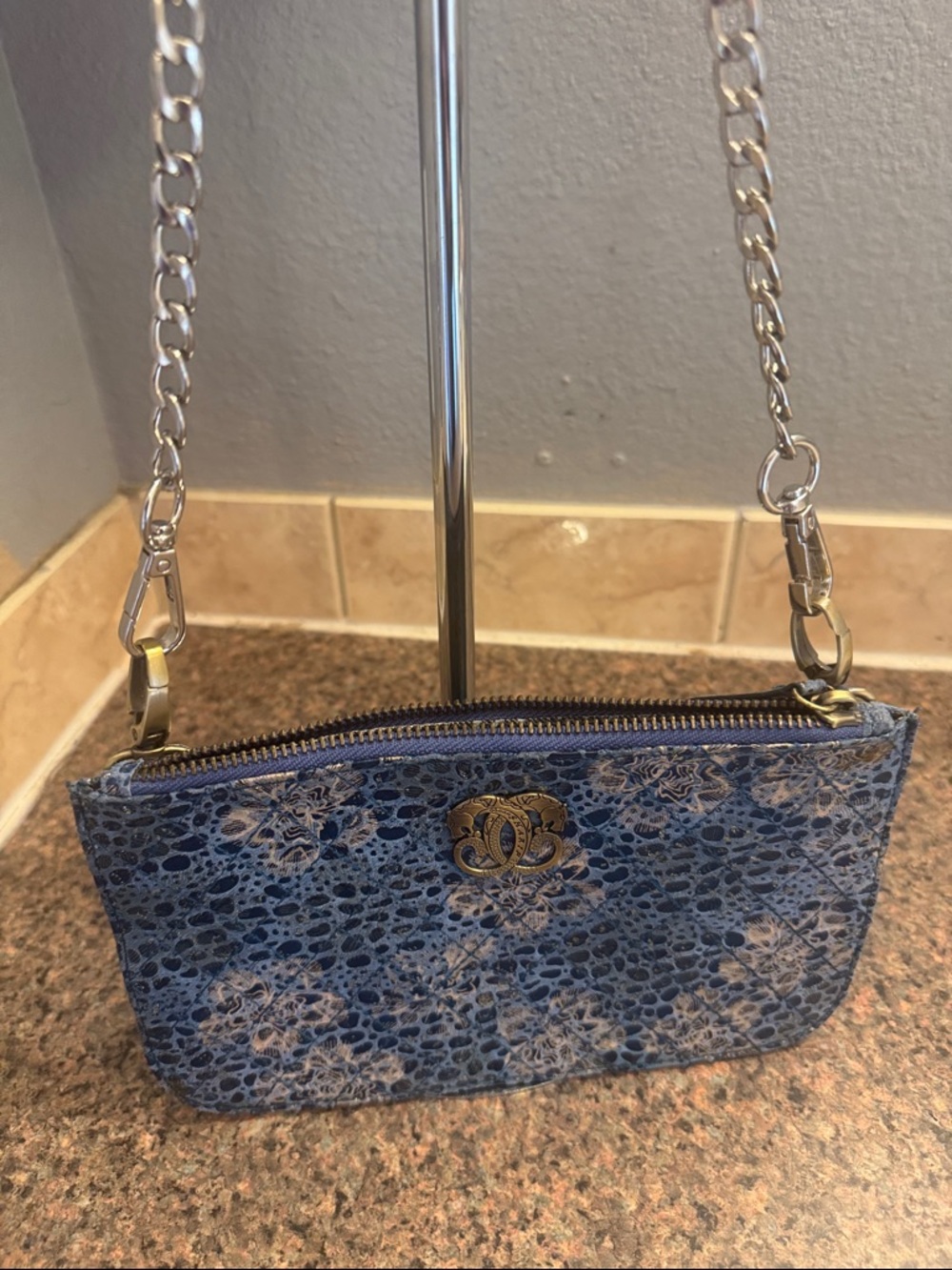 Sharif blue floral print clutch with an unbranded crossbody chain.
